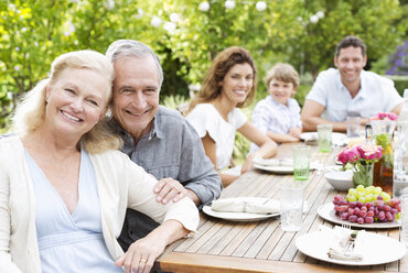 Family smiling at table outdoors - CAIF03391