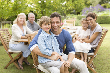 Familie lächelnd am Tisch im Freien - CAIF03405