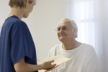 Krankenschwester spricht mit älterem Patienten im Krankenhauszimmer - CAIF03434