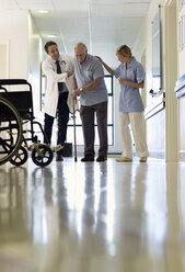 Arzt und Krankenschwester helfen älteren Patienten im Krankenhaus beim Gehen - CAIF03439