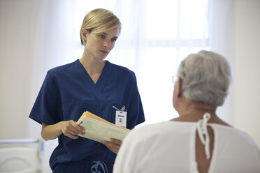 Krankenschwester und älterer Patient unterhalten sich im Krankenhauszimmer - CAIF03442