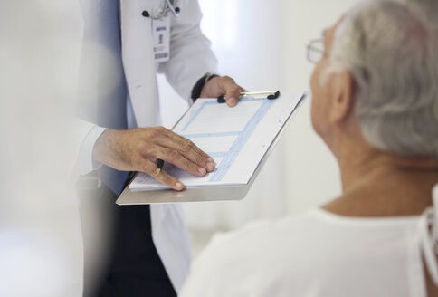 Doctor showing medical chart to patient in hospital room - CAIF03447