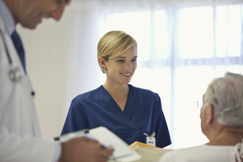 Doctor and nurse talking to older patient in hospital room - CAIF03449