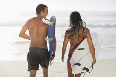 Couple walking with surfboards on beach - CAIF03515