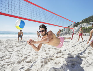 Mann taucht am Strand nach einem Volleyball - CAIF03526