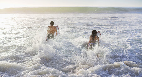 Couple surfing in ocean - CAIF03528