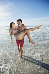 Man carrying woman in ocean surf - CAIF03566