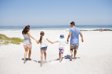 Family holding hands and walking on beach - CAIF03575