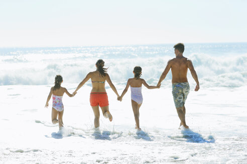 Family running into surf at beach - CAIF03582