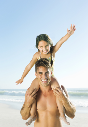 Vater trägt Tochter auf den Schultern am Strand, lizenzfreies Stockfoto