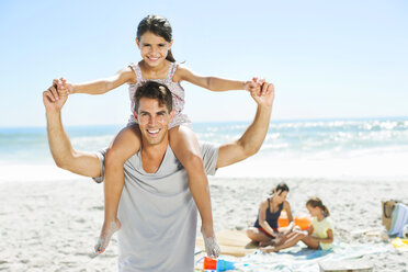 Father carrying daughter on shoulders at beach - CAIF03607