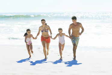 Familie hält Hände und läuft am Strand - CAIF03608