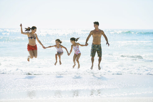 Family jumping in waves on beach - CAIF03611