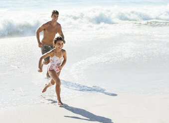 Vater und Tochter laufen in der Brandung am Strand - CAIF03613