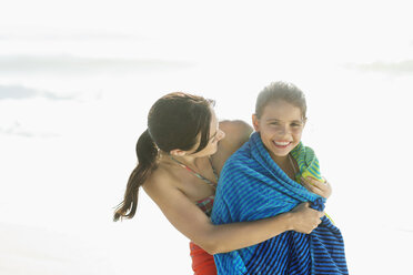 Mutter wickelt Tochter in Handtuch am Strand - CAIF03618