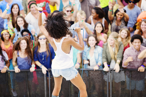 Fans beobachten einen Künstler beim Singen auf einem Musikfestival, lizenzfreies Stockfoto