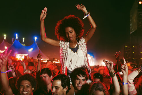 Jubelnde Frau auf den Schultern eines Mannes bei einem Musikfestival - CAIF03634