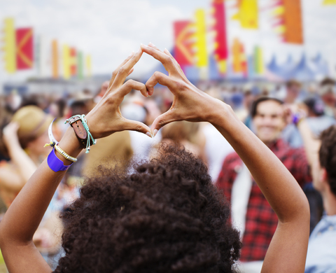Frau formt Herzform mit Händen bei Musikfestival, lizenzfreies Stockfoto