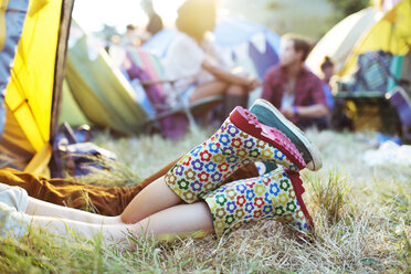 Beine eines Paares ragen bei einem Musikfestival aus dem Zelt - CAIF03648
