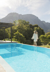 Woman walking along swimming pool - CAIF03706