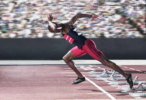 Sprinter, der vom Startblock auf der Bahn abhebt, lizenzfreies Stockfoto