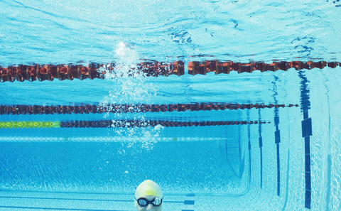 Schwimmer lächelnd unter Wasser im Schwimmbad, lizenzfreies Stockfoto