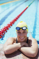 Porträt einer lächelnden Schwimmerin, die sich an den Rand des Schwimmbeckens lehnt - CAIF03777