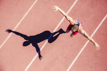 Track and field athlete jumping on track with arms outstretched - CAIF03783