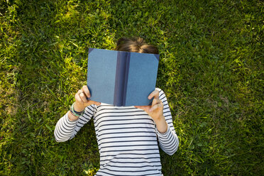 Girl lying on meadow reading a book - LVF06752