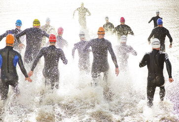 Triathleten in Neoprenanzügen laufen ins Meer - CAIF03814