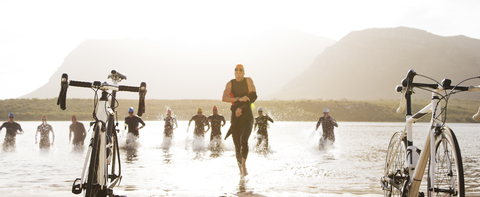 Triathleten laufen zu Fahrrädern am Strand, lizenzfreies Stockfoto