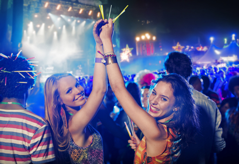 Porträt von jubelnden Frauen mit Leuchtstäben auf einem Musikfestival, lizenzfreies Stockfoto