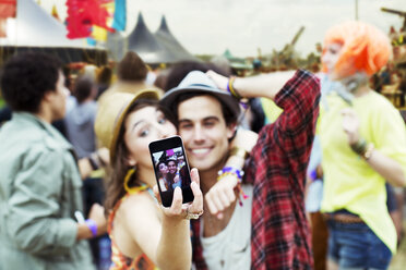 Couple taking self-portrait with camera phone at music festival - CAIF03944