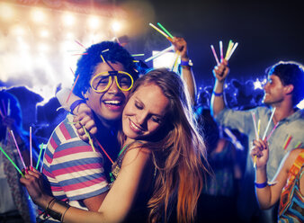 Couple with glow sticks hugging at music festival - CAIF03948