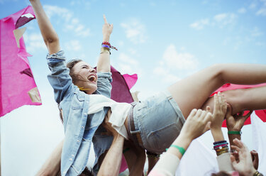 Enthusiastic woman crowd surfing at music festival - CAIF03951