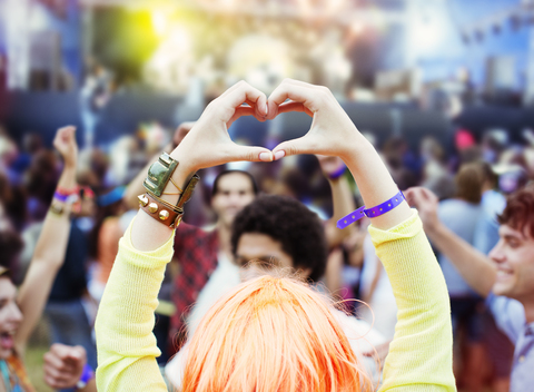 Frau formt Herzform mit Händen bei Musikfestival, lizenzfreies Stockfoto