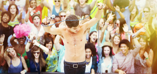 Tanzender Künstler auf der Bühne mit jubelnden Fans im Hintergrund bei einem Musikfestival - CAIF03961