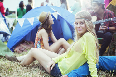 Porträt einer Frau, die mit Freunden vor dem Zelt eines Musikfestivals abhängt - CAIF03964