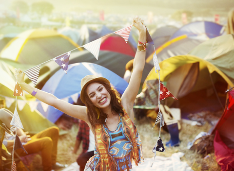 Portrait of enthusiastic woman outside tents at music festival stock photo