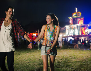 Couple holding hands and leaving music festival - CAIF03980