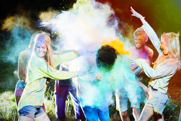 Friends throwing chalk dye on man at music festival - CAIF03987