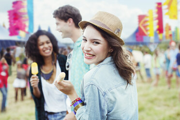 Porträt einer Frau, die mit Freunden auf einem Musikfestival aromatisiertes Eis isst - CAIF03994