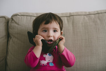 Baby girl playing with two mobilephones at home - GEMF01892