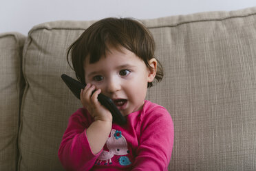 Baby girl talking on mobile phone at home - GEMF01893