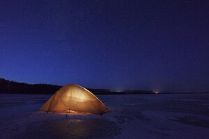 Russland, Oblast Amur, beleuchtetes Zelt auf dem zugefrorenen Fluss Zeya bei Nacht unter dem Sternenhimmel - VPIF00377