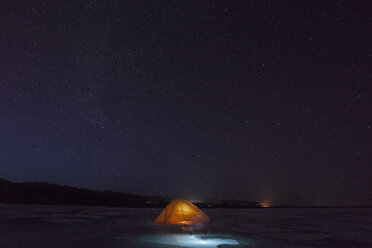 Russia, Amur Oblast, illuminated tent on frozen Zeya River at night under starry sky - VPIF00378