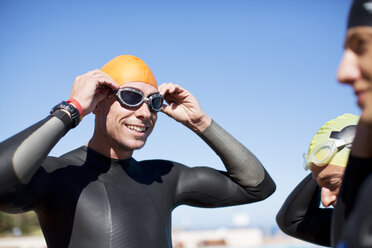 Triathlete adjusting goggles outdoors - CAIF04060