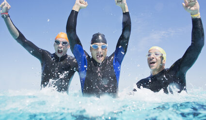 Triathletes in wetsuits splashing in waves - CAIF04061