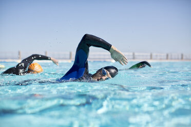 Triathletes in wetsuits racing in pool - CAIF04072