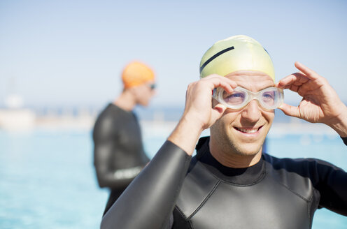 Triathlete adjusting goggles outdoors - CAIF04073
